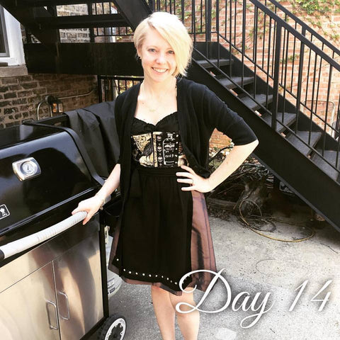 girl standing at a grill wearing a dirndl with a black dirndl blouse and sweater