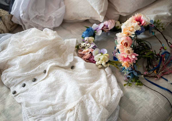 a white cotton dirndl blouse laying on a bed with floral crowns