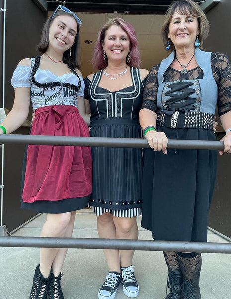 Three generations of women all wearing black, red and grey gothic inspired dirndl looks. The woman of the popular German band the Klaberheads