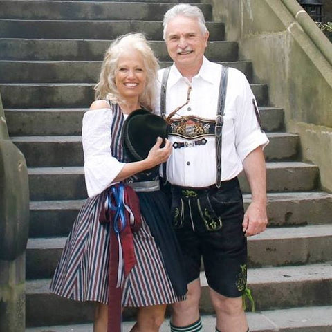 Couple wearing traditional outfits. The woman is in a traditional dress and man is in a lederhosen