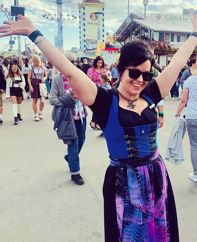 woman with short hair wearing a black and blue dirndl with black dirndl blouse at oktoberfest
