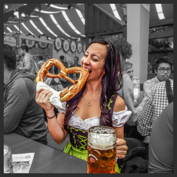 Ashley smith from mywanderlustylife.com eating a very giant pretzel and wearing a traditional oktoberfest outfit at oktoberfest