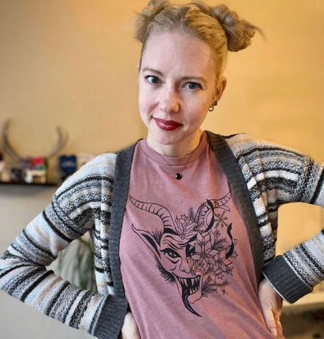 woman with pigtails wearing a mauve krampus t-shirt and a striped sweater