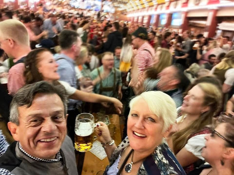 busy photo of people dancing at the oktoberfest beer tents holding their own beer and enjoying fun fair