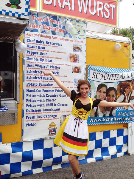 woman from the schnitzels n giggles food truck wearing a German dirndl dress posing at wurstfest in new braunfels tx celebrating German culture