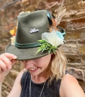 Green wool Bavarian Hat with flowers, feathers and pins worn by a woman.