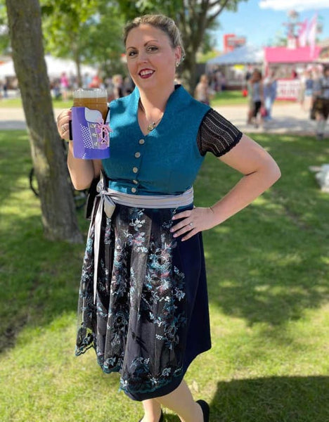 Woman wearing a high neckline teal plus size dirndl with floral apron holding a liter of beer