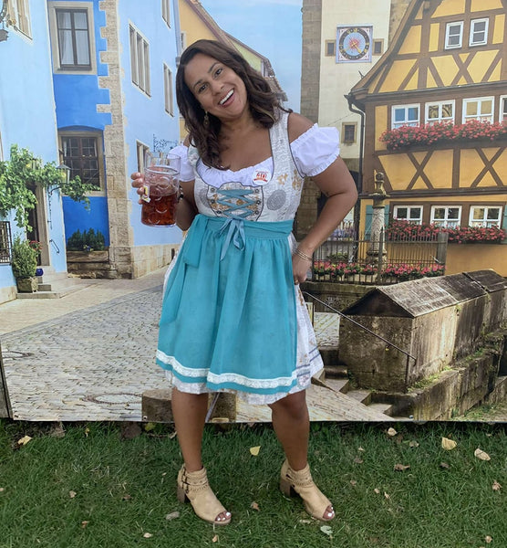 woman smiling in a white and grey dirndl with teal apron at German fest Milwaukee 