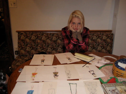 Woman sitting at table in front of many types of dirndl designs