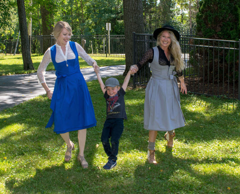 two women wearing dirndls playing with a little boy in a baseball cap