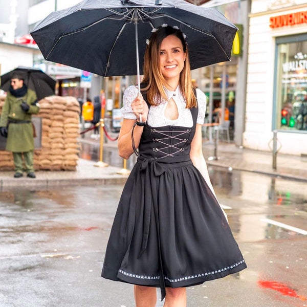 woman holding an umbrella wearing a black dirndl with a white blouse in Germany - traditional dress for Bavarian celebrations