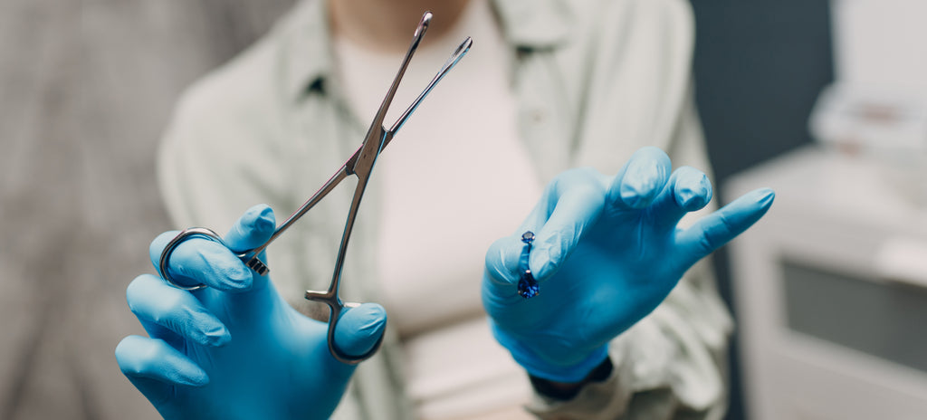 A piercing professional who is showing the type of belly piercing jewellery that she will be using.