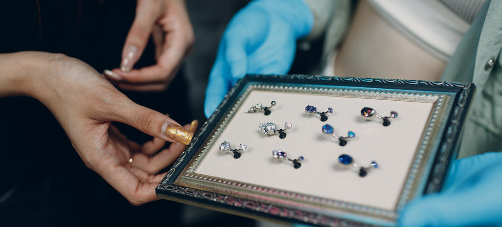 A customer being shown that there are a variety of belly piercing jewellery options.