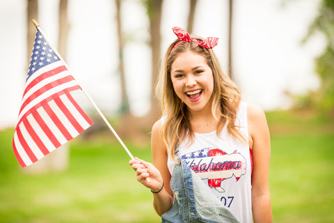 Lush Fashion Lounge American Summer collection | Oklahoma patriotic apparel, Oklahoma graphic tank tops, Oklahoma women's apparel. Model wearing Oklahoma buffalo tank top waving American flag