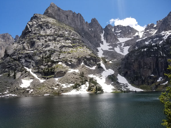 View of blue skies and a mountain peak towering over a lake 