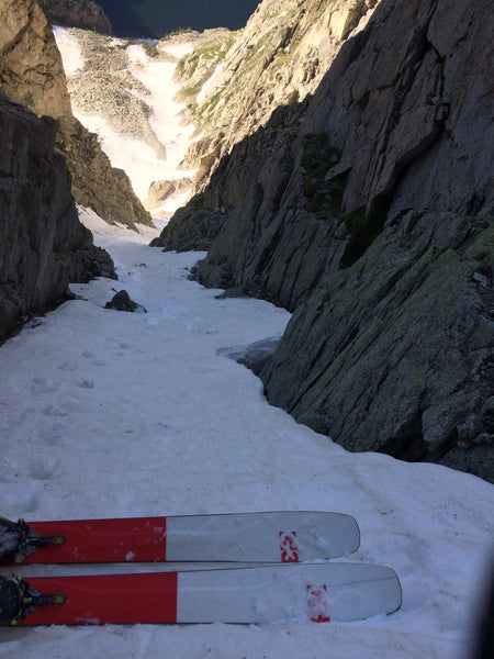 two red skis perched atop a narrow snow chute 