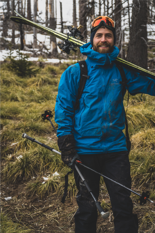 a backcountry skier smiles despite sparse snow coverage