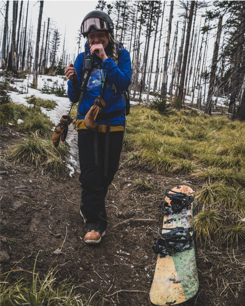 A splitboarder laughing beside patchy snow