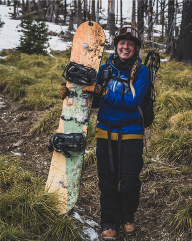 a splitboarder smiles despite sparse snow coverage
