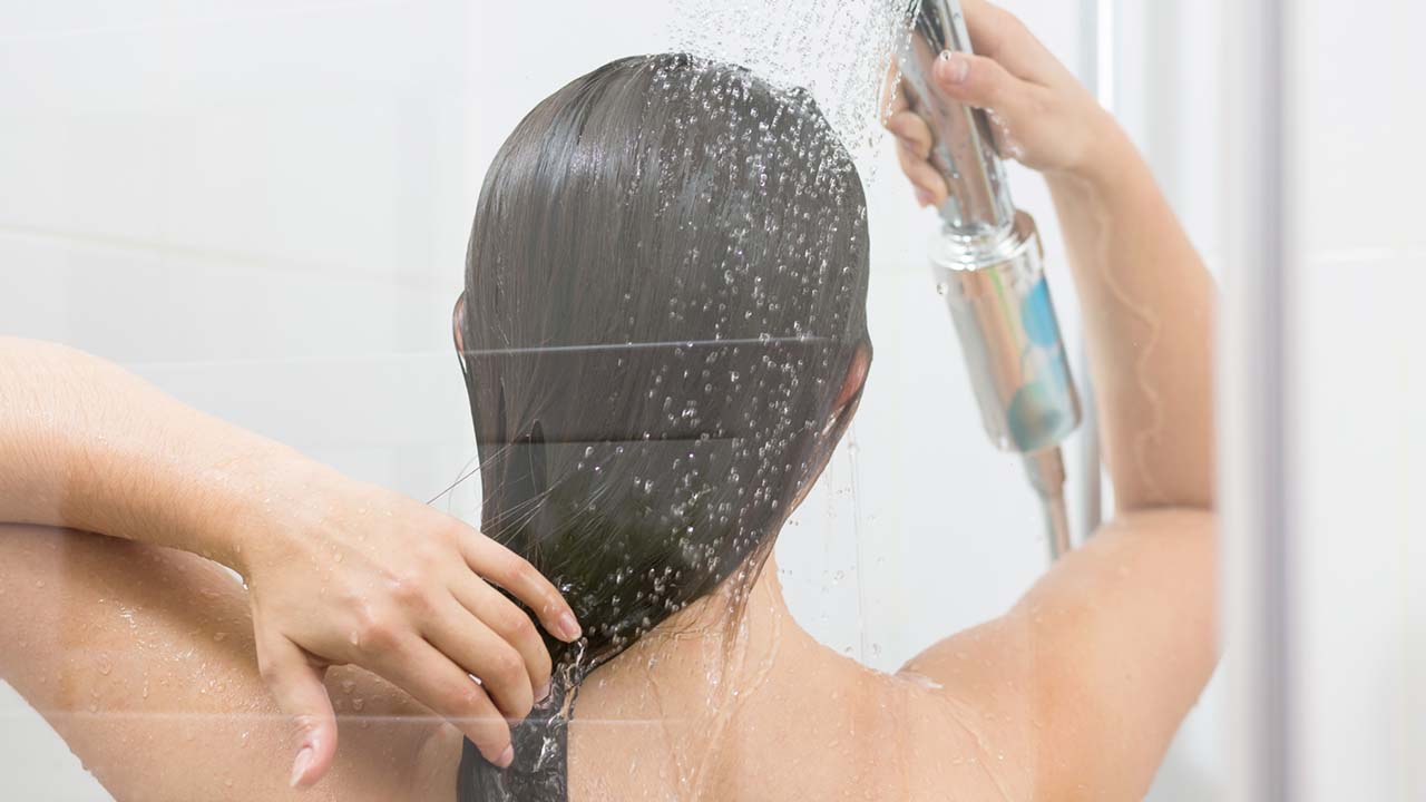Mulher lavando o cabelo com shampoo sem sulfato no combate à caspa