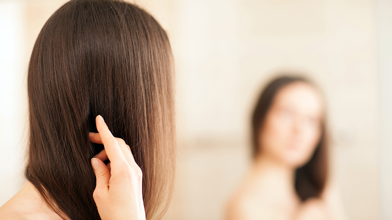 Mulher olhando seu cabelo liso no espelho