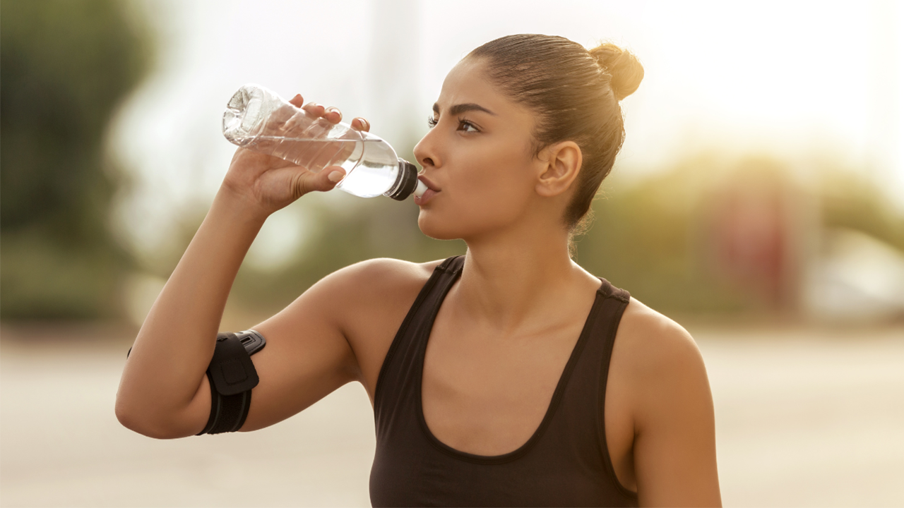 Mulher tomando água enquanto pratica exercício