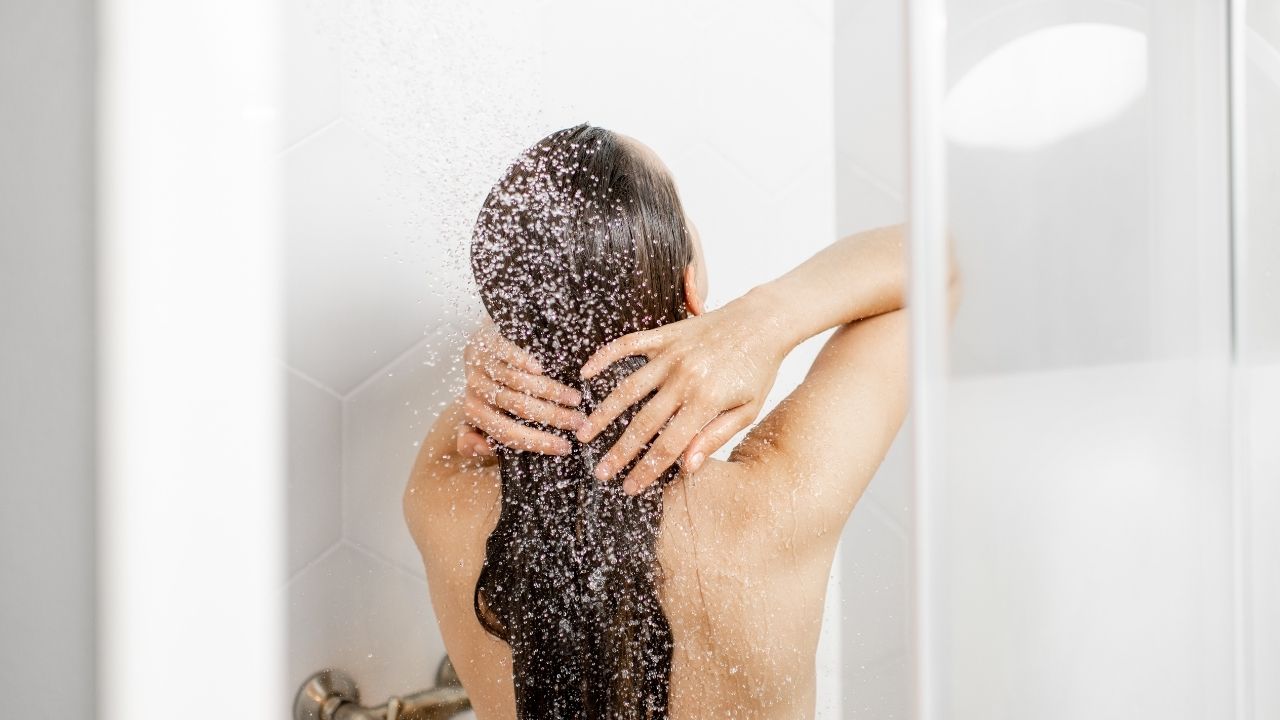 Mulher lavando o cabelo com a técnica low poo, no poo e co-wash