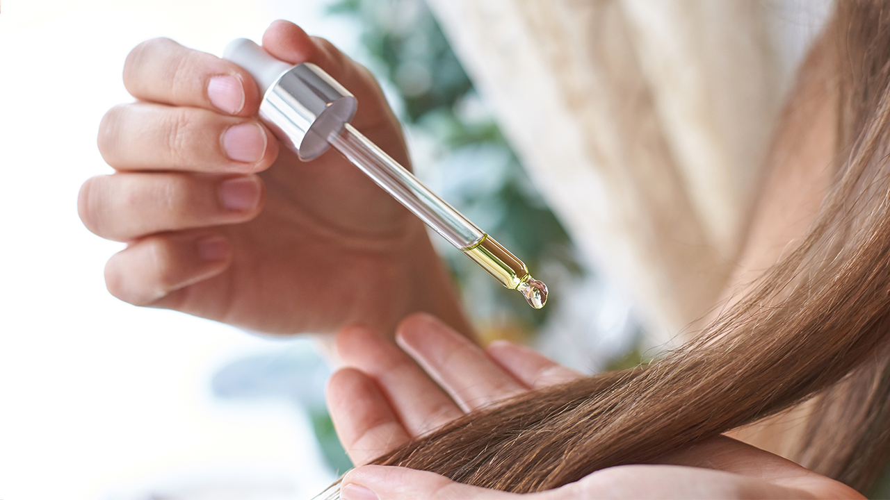 Mulher aplicando óleo de argan no cabelo
