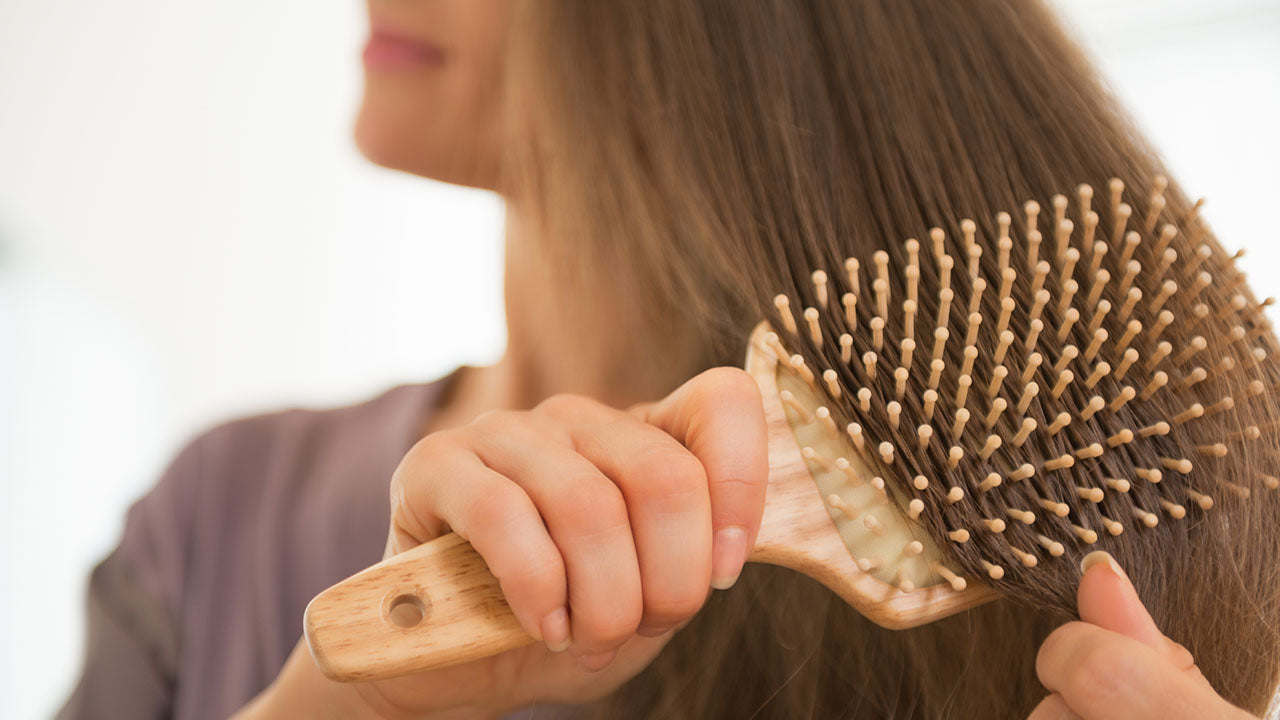 Mulher escovando o cabelo após tratamento com óleo de manketti