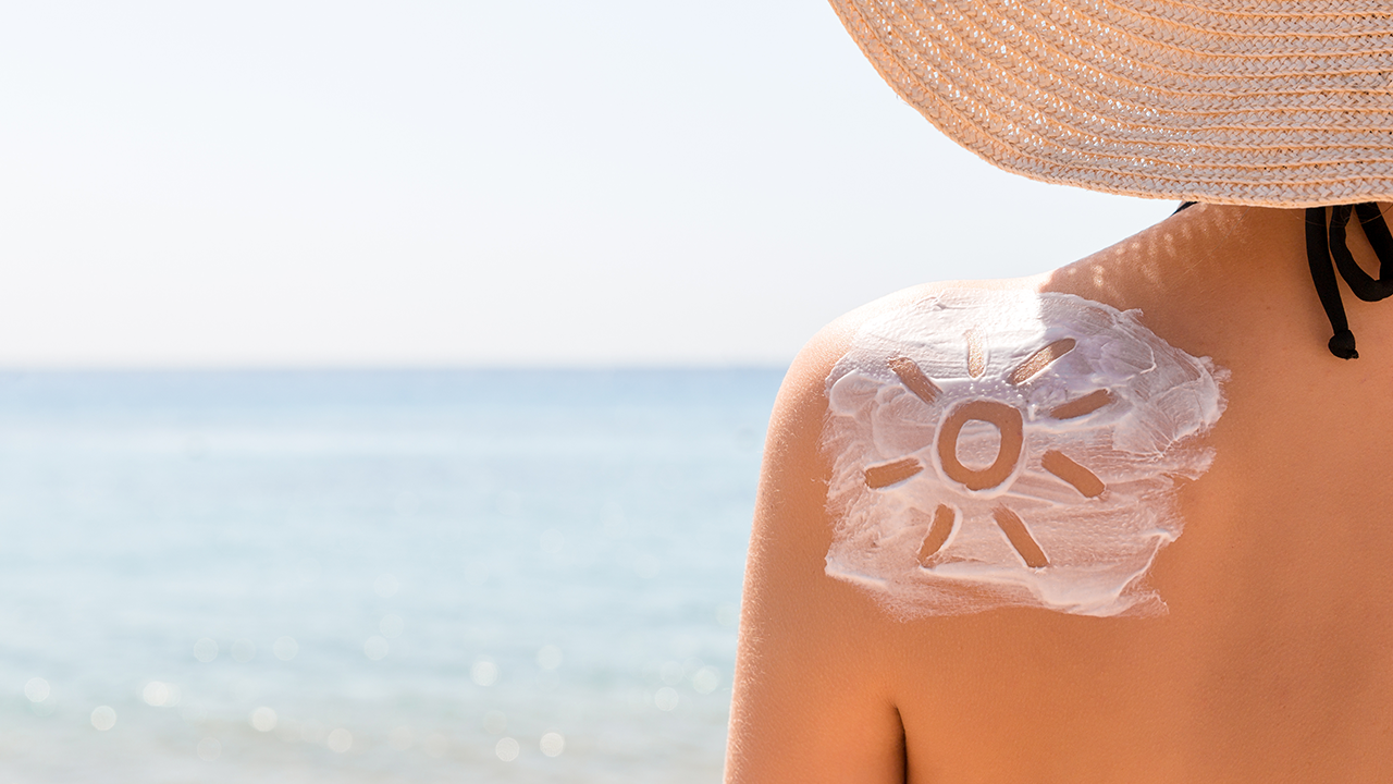 Mulher com protetor solar nas costas na praia