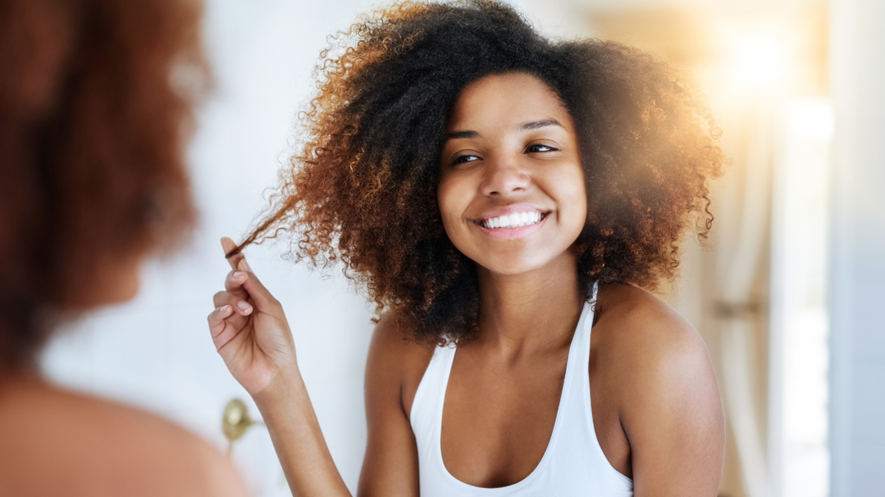 Mulher crespa olhando seu cabelo no espelho