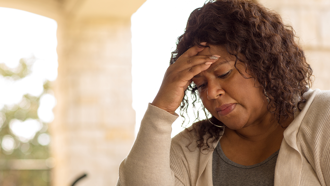 Mulher pensando sobre os efeitos da menopausa no cabelo, pele e corpo