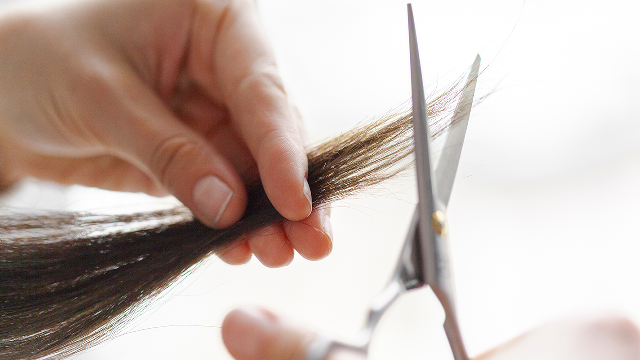 Pessoa cortando o cabelo de uma mulher