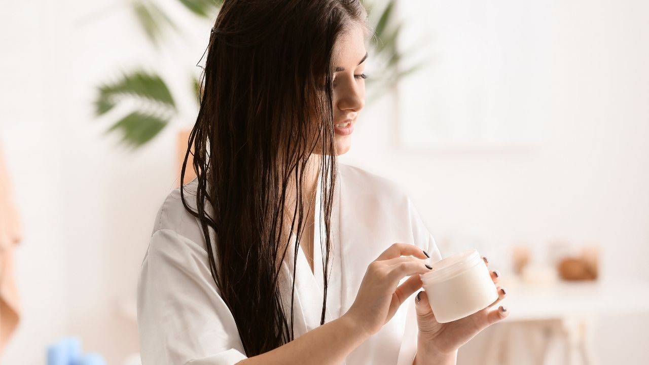 Mulher aplicando manteiga de manga no cabelo úmido