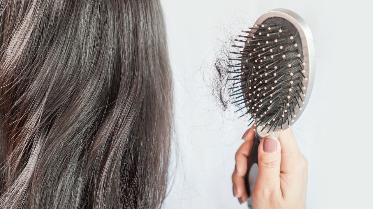 Mulher mostrando sua escova cheia de cabelo perdido