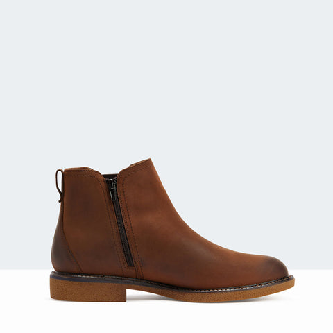 Brown Minnesota boot by Hush Puppies shown from outer profile with dark brown ankle elastic & a white/grey background.