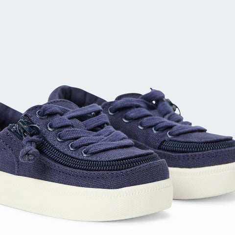 Classic Low-rise Canvas Sneaker with navy upper and a white sole shown from the side in front of a grey and white backing.