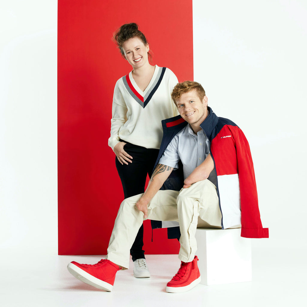 Alt text: Man & woman in front of red & white background, the man is seated on a podium highlighting the red Classic Hi-Top sneaker.