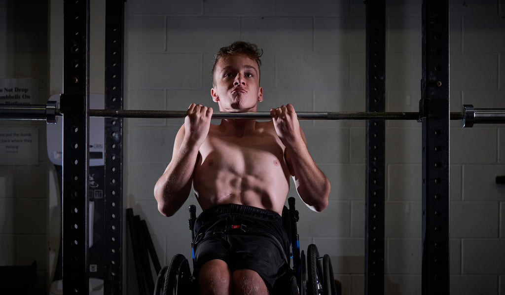 Jaden, a young Para athlete doing a pull up.