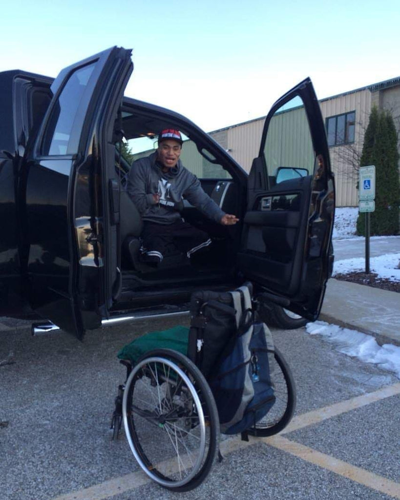 Barney, a young NZ man is sitting in his car with his wheelchair at the front. 