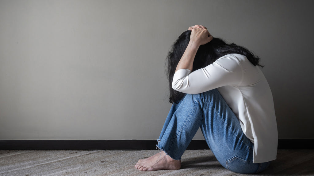 depressed woman sitting on floor holding her head