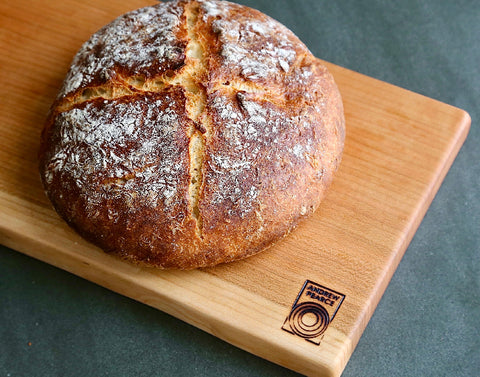 Freshly baked bread on a wood cutting board from Andrew Pearce Bowls
