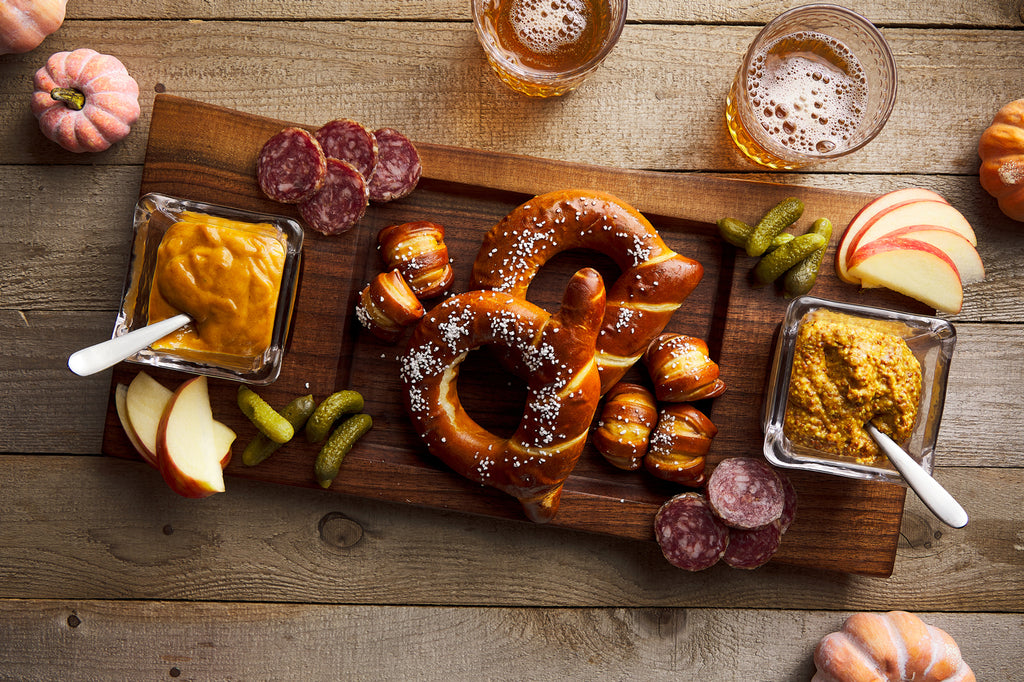 charcuterie board shown with simon pearce glass, cured meets, home made pretzels, mustards and other savory and sweet snacks