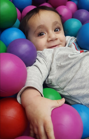 Happy baby laying in a ball pool
