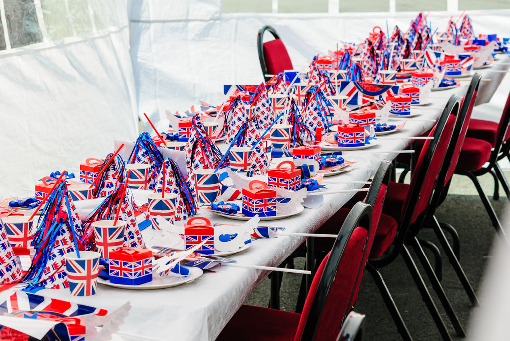 Long white table decorated with flat and red white and blue decor red chairs