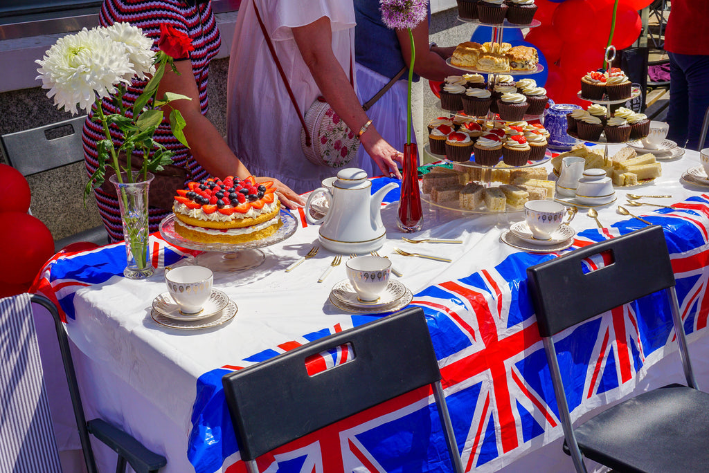 Party goers walk past flag draped table filled with desserts 