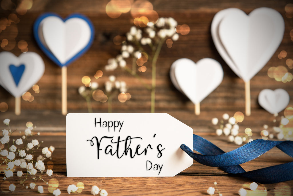 White fathers day gift tag with blue ribbon on wooden surface with cut out white hearts 
