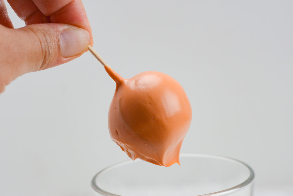 Blondie Truffle covered in orange candy melts drip into cup after dipping