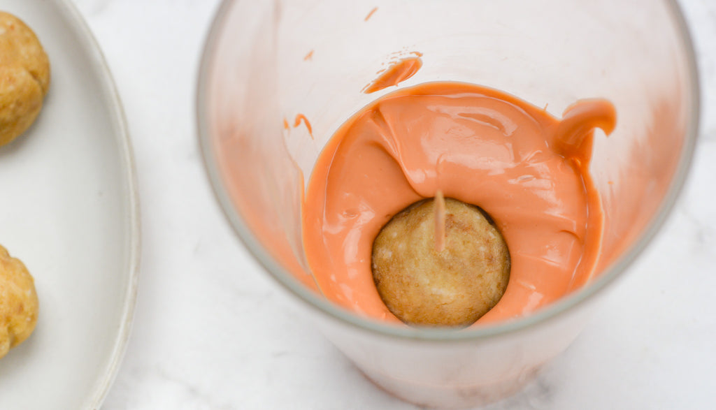Truffle submerged in orange candy coating inside of a tall glass