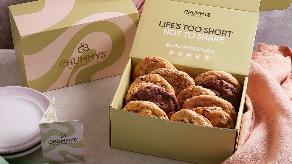 A box of variety cookies sits on a table with the top open. Cookies peek out of the box.